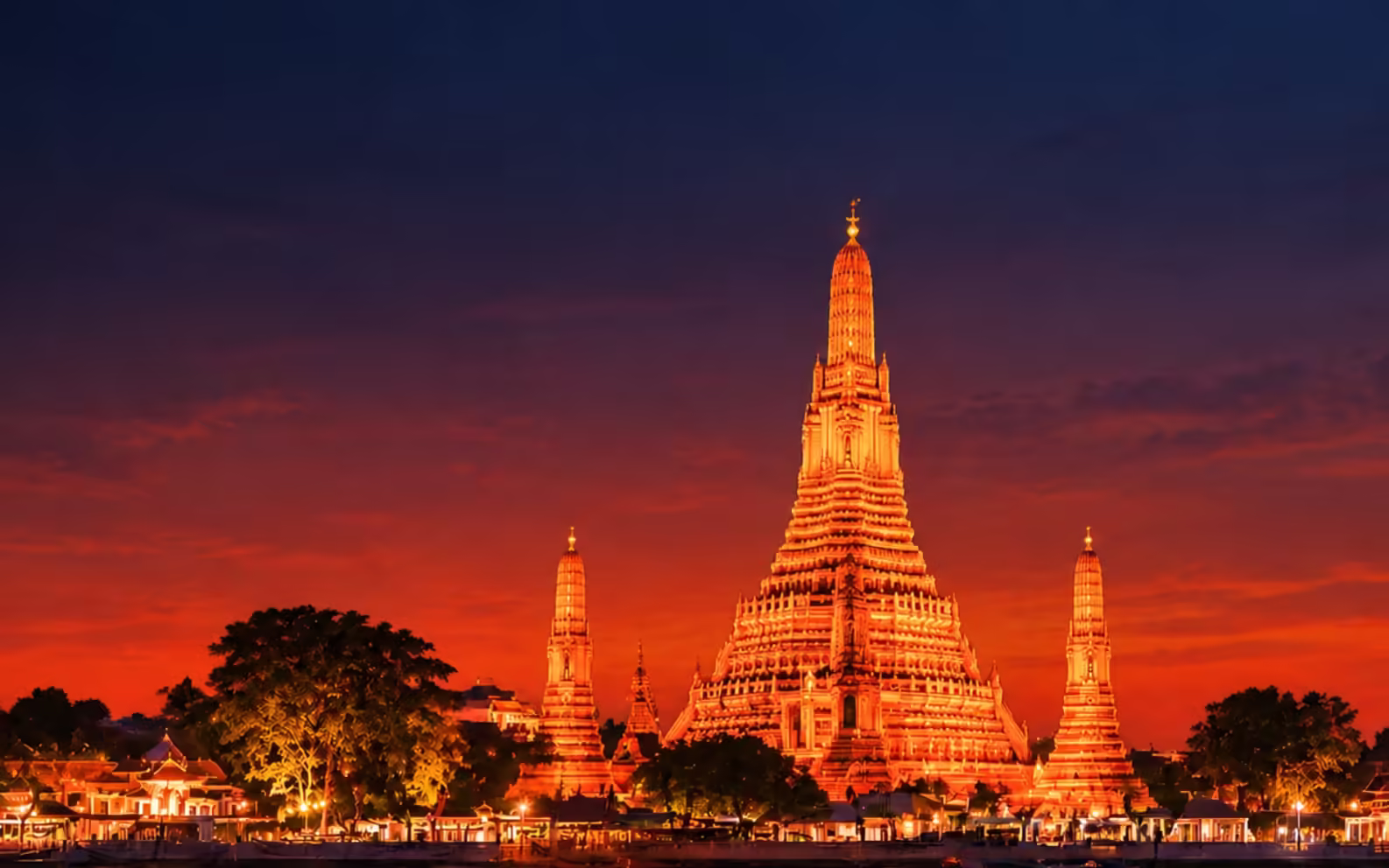 Wat Arun temple illuminated in gold at dusk, reflected in the Chao Phraya River in Bangkok, Thailand
